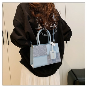 Detail of light blue patchwork handbag with round handles and adjustable strap