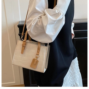 Detailed texture of white crocodile embossed leather handbag with brown handles