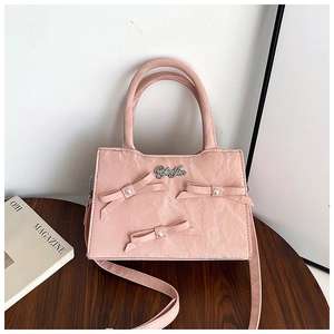 Détail du sac à main rose avec texture froissée vintage et nœud 3D orné d'une perle