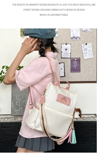 Close-up of minimalist cream backpack with pink straps and decorative tassel charm details