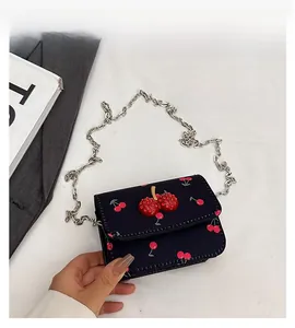 Close-up of black crossbody bag featuring red cherry prints and 3D rhinestone cherry charm