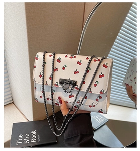 Détail d'un sac en cuir PU blanc avec imprimé cerises rouges et bandoulière chaîne épaisse