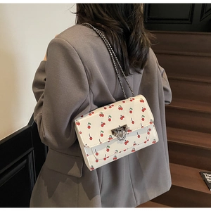 Détail du sac cerise avec fermoir métallique vintage et bandoulière chaîne à l'épaule