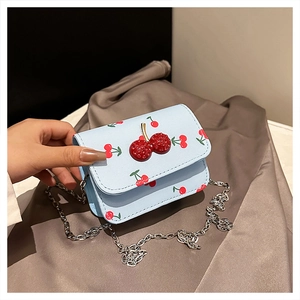 Detail of light blue cherry print mini bag with a red cherry shaped metal buckle