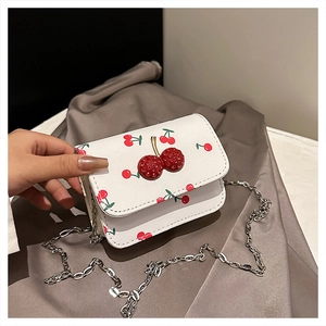 Detail of white crossbody bag with red cherry pattern and 3D rhinestone buckle