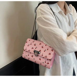 Détail du sac bandoulière rose avec imprimé cerise et bandoulière en chaîne métal