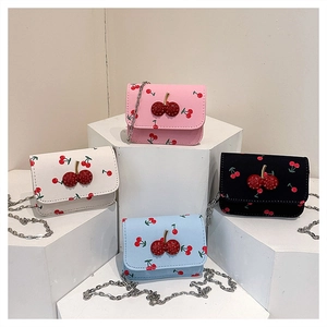 Detail of four small crossbody chain bags with red cherry prints and 3D cherry charms