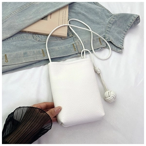 Detail of white lychee pattern leather mini bag with woven knot strap on casual background