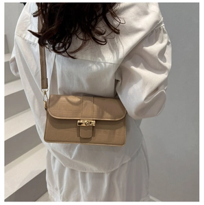 Detail of light brown crocodile-embossed leather handbag with golden bamboo-shaped twist lock