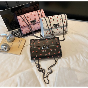 Vue détaillée des sacs bandoulière imprimé cerise en rose, noir et blanc avec chaîne