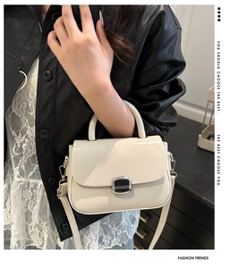 Detail of cream white square handbag with polished metal buckle and top handle