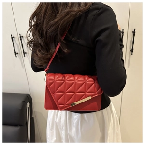 Détail du sac à bandoulière matelassé rouge avec coutures et garniture dorée