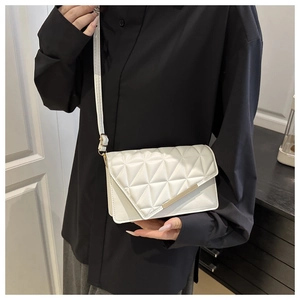 Détail du sac à bandoulière matelassé blanc avec bordure en métal doré sur similicuir texturé