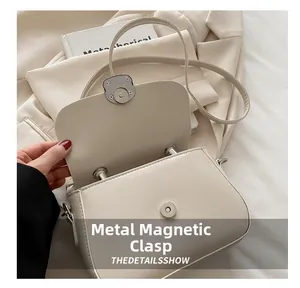Detail of cream white leather handbag featuring a secure round metal magnetic buckle