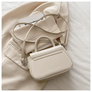 Detail view of cream structured handbag with silver hardware on elegant fabric background
