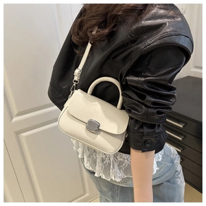 Detailed view of cream white crossbody bag with silver buckle worn by a model