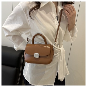 Close-up of caramel leather crossbody bag with silver buckle and structured top handle