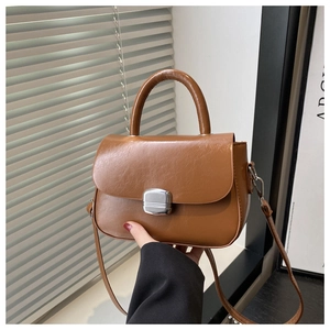 Detail of brown vintage crossbody bag with silver metal buckle and top handle