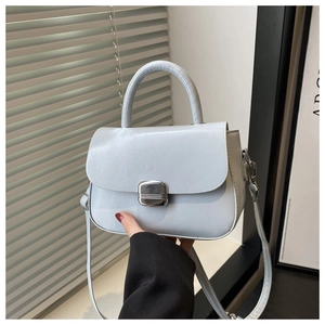 Detail of light blue crossbody bag with silver buckle and textured handle