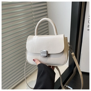 Detail view of cream leather square bag with silver clasp and top handle for women