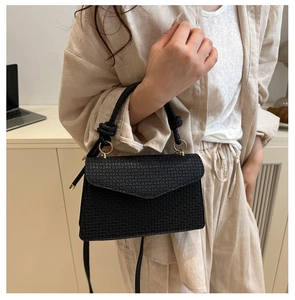 Détail du sac à bandoulière noir texturé avec poignée nouée et finitions métalliques