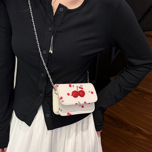 Mini cream saddle bag with cherry pattern and rhinestone detail with silver chain strap