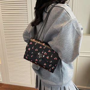 Small cherry print black crossbody chain bag worn by a model in a trendy summer style