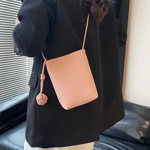 Pink textured leather bucket bag with knot charm worn over a black blazer outfit