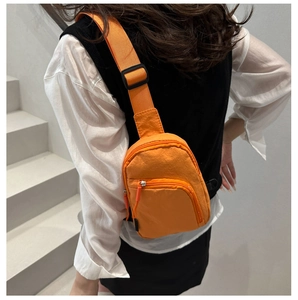Vue détaillée d'un sac banane orange vif porté en bandoulière sur un modèle en intérieur