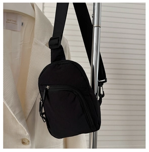 Détail du sac de poitrine en nylon noir avec plusieurs zips et bandoulière réglable