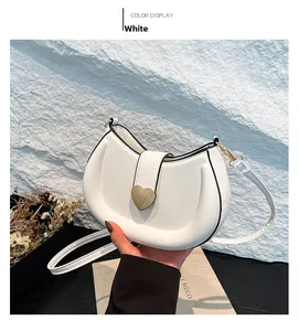 Detailed view of white crescent bag with gold heart clasp and black oil edge finish