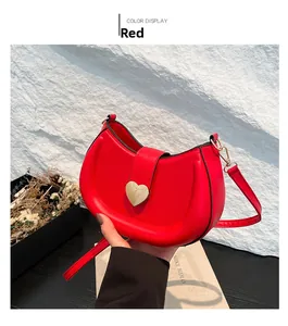 Detail view of red semi-circle crossbody bag featuring a golden heart-shaped metal buckle