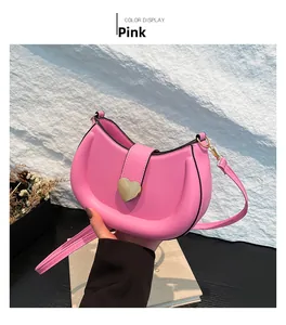 Detail of pink half-moon crossbody bag with gold heart buckle and adjustable strap