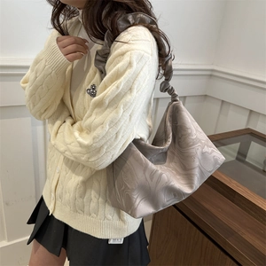 Cloud-shaped marble print shoulder bag with pleated straps in a minimalist indoor setting