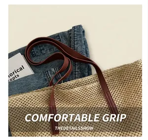 Detail of hand-woven straw tote bag showing brown leather handles and mesh texture