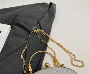 Detail of silver glitter clutch bag with gold chain and rhinestone flower handle