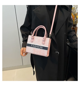 Détail d'un sac à main rose avec motif marbre et sangle noire sur un manteau noir