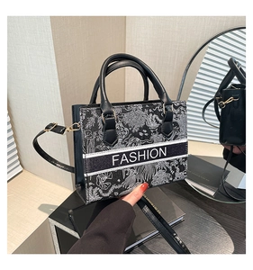Détail du sac cabas noir avec broderie florale blanche et texte du logo Fashion