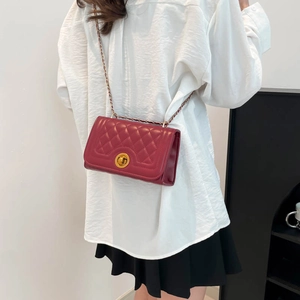 Deep red quilted crossbody bag with gold chain strap shown on a model in a casual outfit