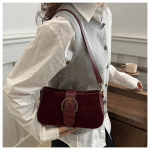 Detail of burgundy suede underarm bag with large gold buckle and smooth leather strap