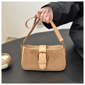Détail du sac sous le bras en daim mat kaki avec boucle dorée et bandoulière