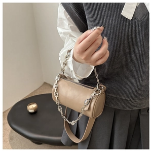 Close-up of beige cylindrical bag with chunky silver chain and leather strap
