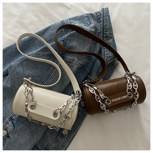 Détail de sacs cylindriques à chaîne minimalistes en beige et marron sur denim