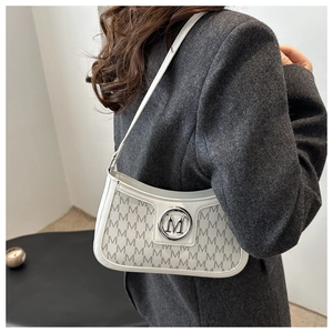 Close-up of white faux leather underarm bag featuring grey letter print and silver M logo