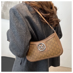 Detail of vintage brown monogram handbag worn with grey suit blazer by a model