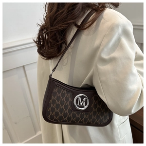 Detail of dark brown vintage monogram shoulder bag with silver M logo worn by a model