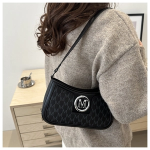 Detail of black underarm bag featuring silver metal M logo and all-over letter embossing