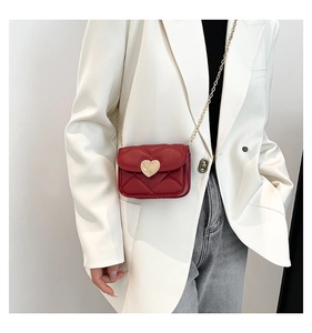 Détail d'un mini sac matelassé rouge foncé avec fermoir cœur doré et bandoulière chaîne