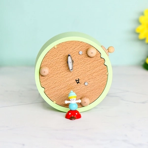 Bottom view of light green Ferris wheel music box with wooden base and metal winding key