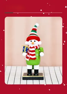 Festive snowman nutcracker ornament with striped hat holding a blue gift box on stand